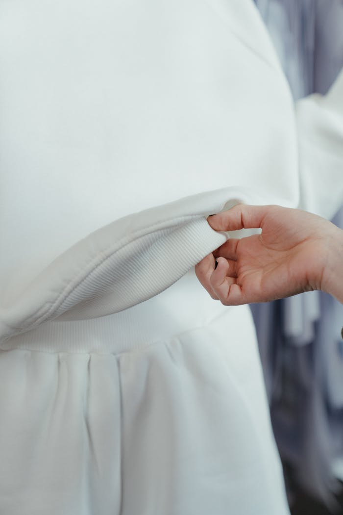 Detailed view of a hand holding white fabric, inspecting quality in a workshop setting.